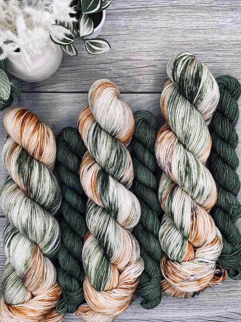 Three skeins of multicolored yarn on a wooden surface with decorative elements.