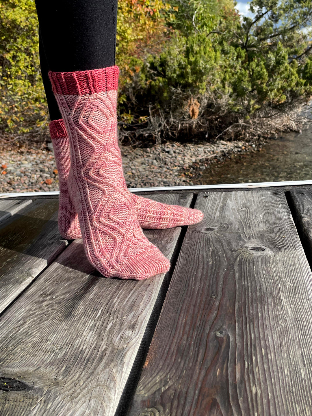 Pink knitted socks on a wooden deck with a natural background