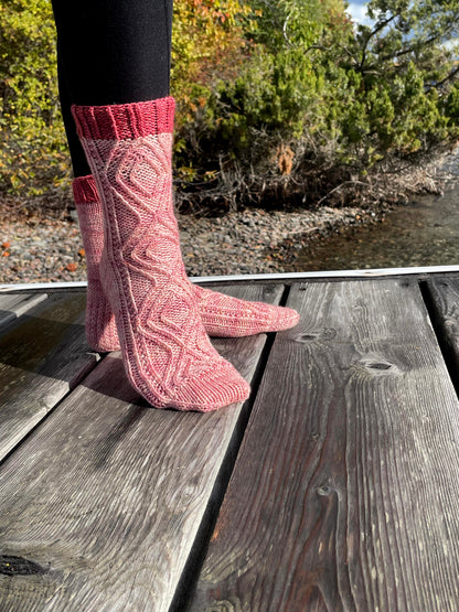 Pink knitted socks on a wooden deck with a natural background