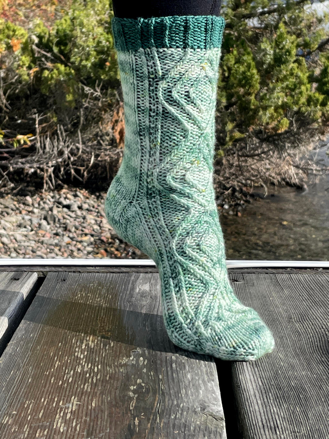 Green knitted sock on a wooden surface with a natural background