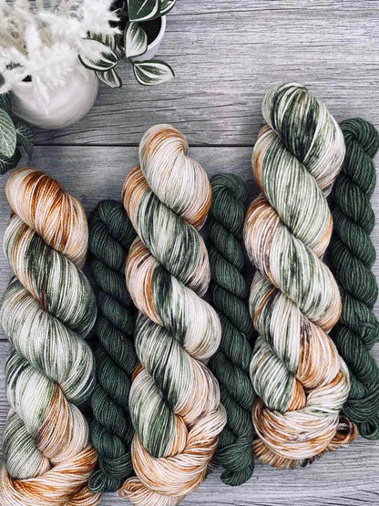 Three skeins of multicolored yarn on a wooden surface with decorative elements.